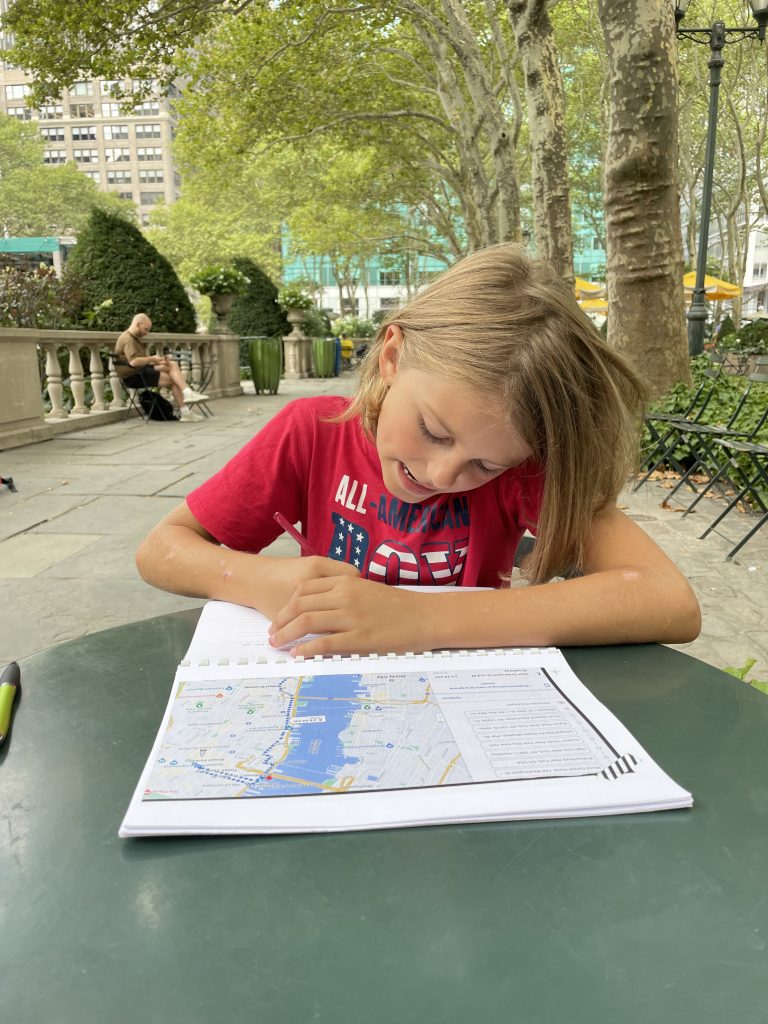 Kind schreibt in ein Heft im Park