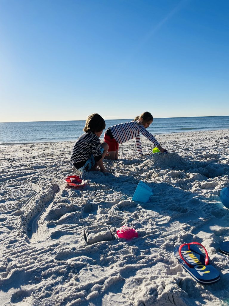 Kinder spielen im Sand am Meer