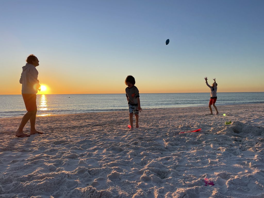 Vater und Kinder spielen am Strand Football